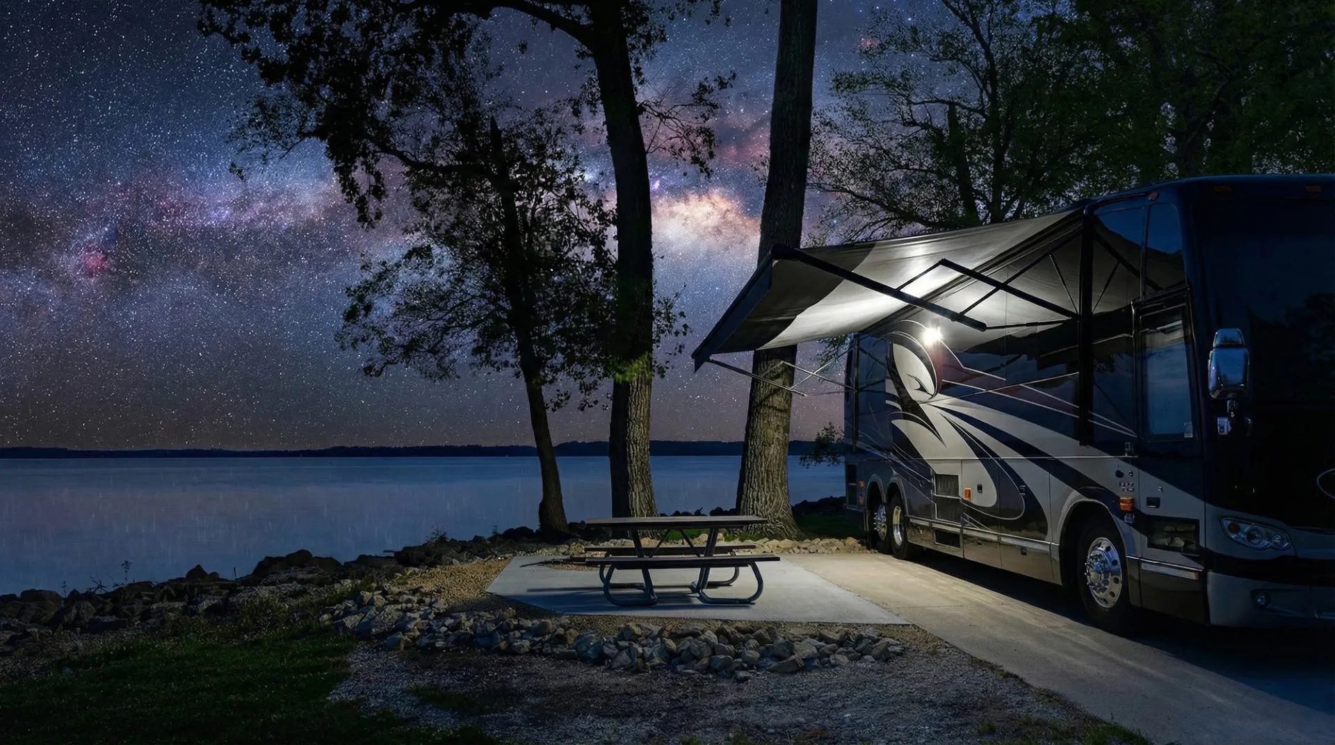 A motorhome parked at a lakeside campsite under a starry sky